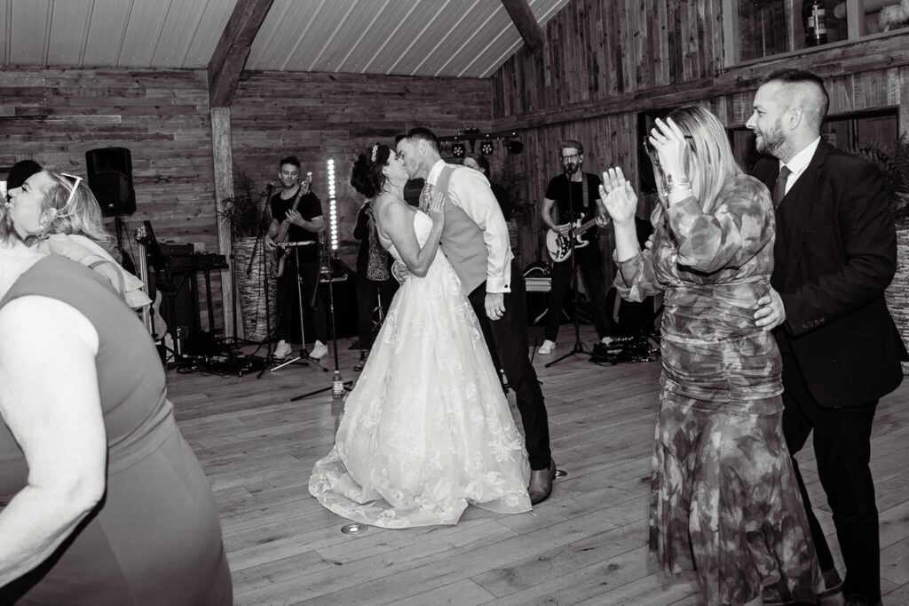 Bride and groom first dance with live wedding band performing behind them and guests dancing