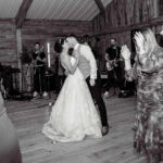 Bride and groom first dance with live wedding band performing behind them and guests dancing