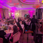 Corporate event at Manchester Hall with live 5-piece band and sax performing to seated guests under pink uplighting