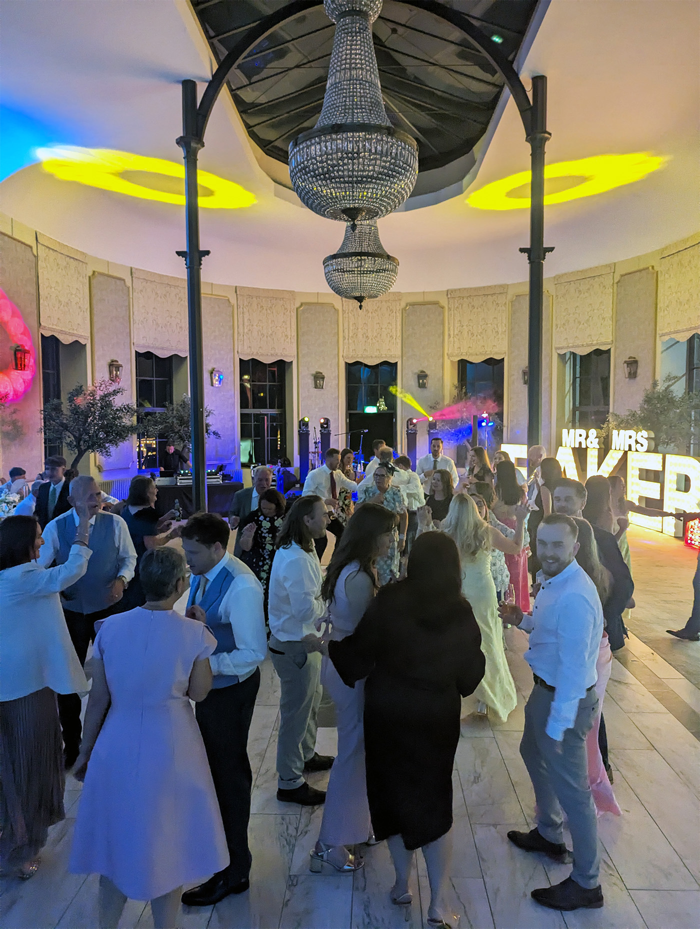 Guests dancing beneath the chandelier at Wynyard Hall during William’s wedding reception with Groove Manuva live band.