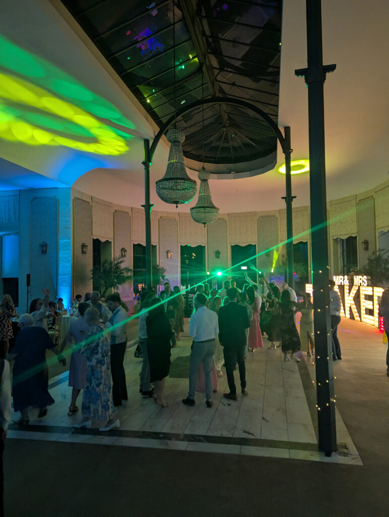 Wedding guests dancing at Wynyard Hall with colourful lighting and live band performing.